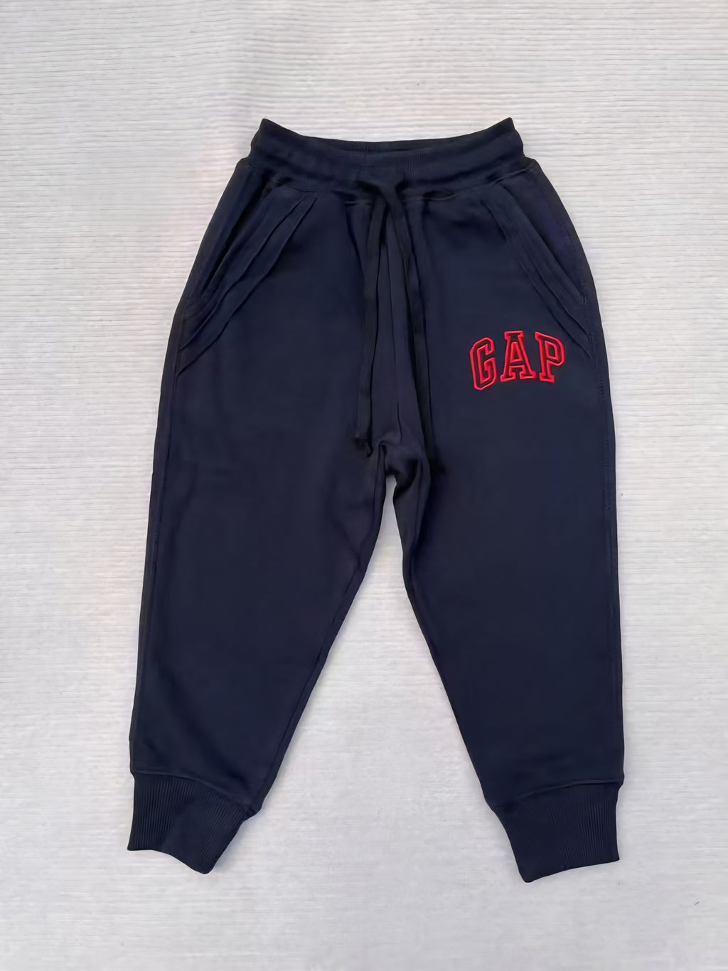 Navy blue sweatpants with 'GAP' logo on a light gray background
